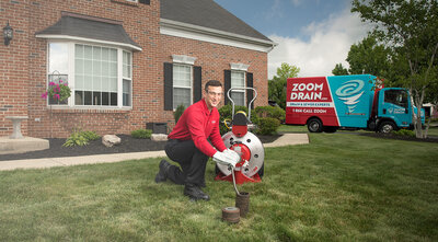 Zoom Drain service professional using a drain snake to clean outside sewer pipe